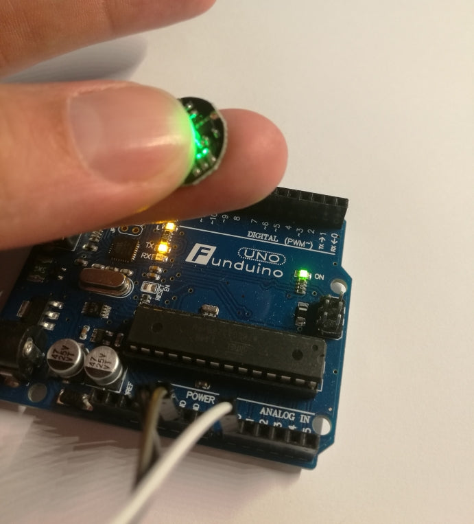 Runder Puls-Sensor mit drei Anschlusskabeln an einem Finger