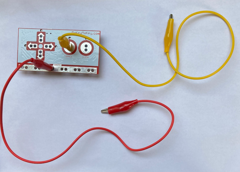Eine Krokodilklemme wird in den Makey-Makey eingesteckt